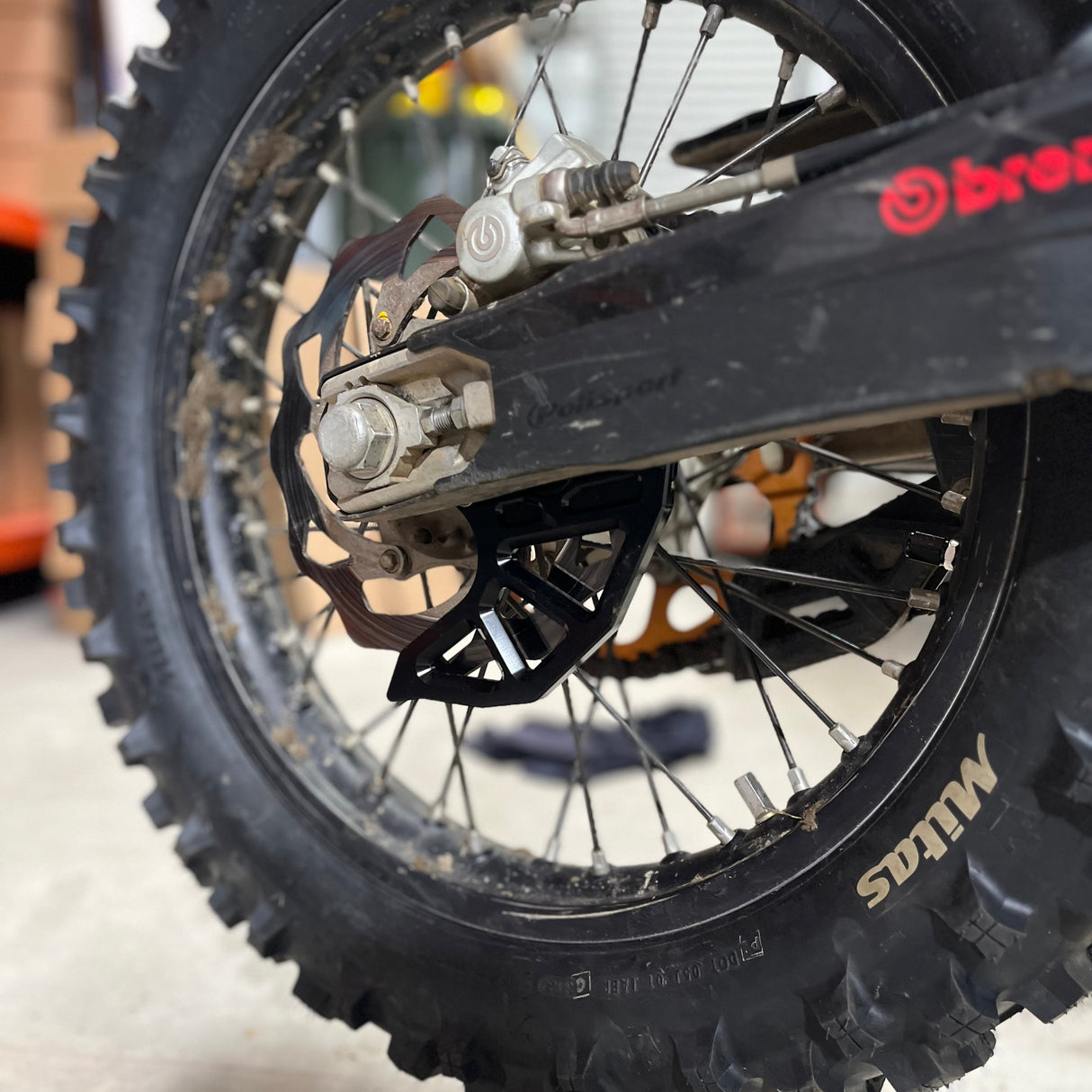 Straight-on view of the CNC‑machined aluminium rear brake disc guard (KTM 2005–2023), showing its matte black anodised finish and integrated caliper support.